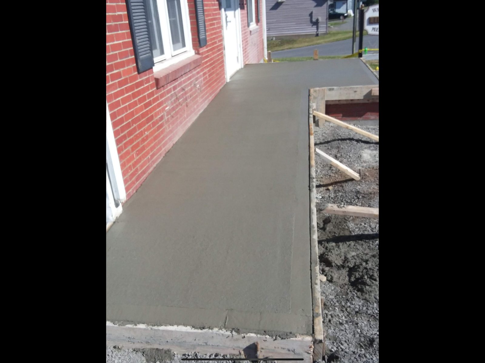 Fresh concrete walkway poured next to brick building