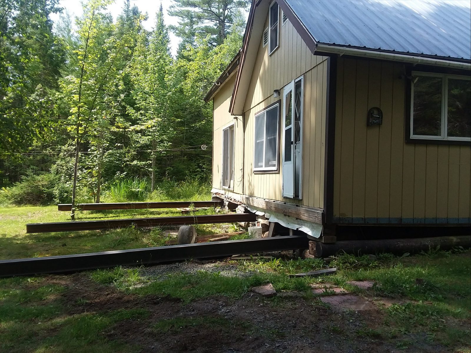 Cabin being structurally lifted on steel I-beams for foundation replacement work